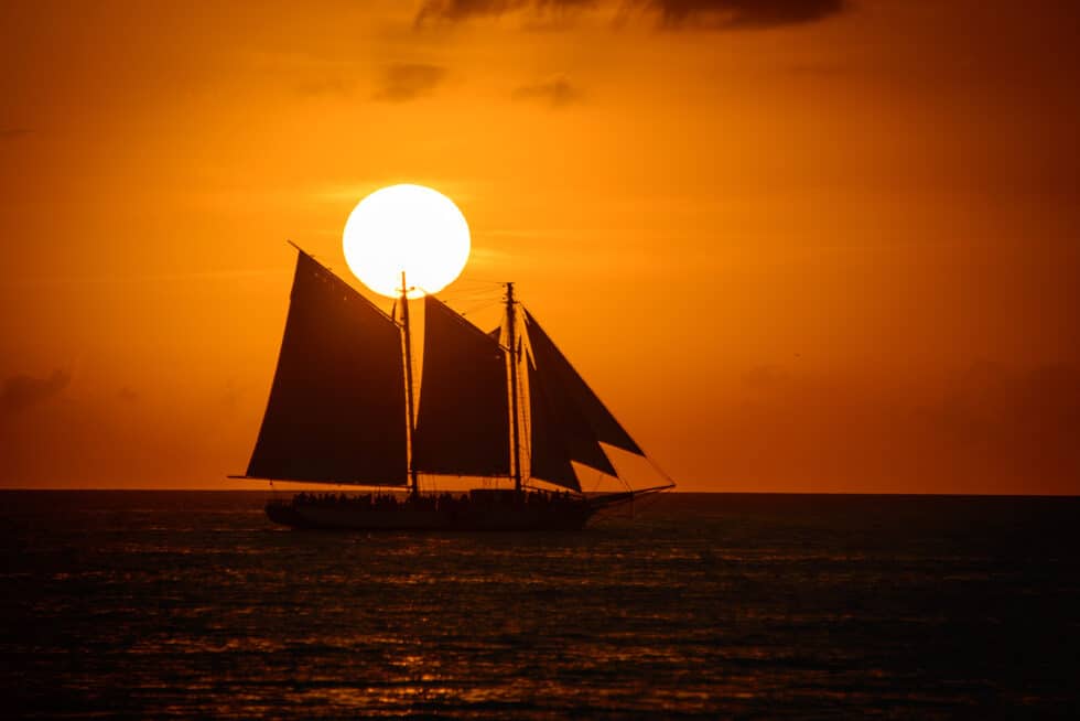 Vacation Travel Innovation sunset sailing scene in the Florida Keys with a silhouetted sailboat.